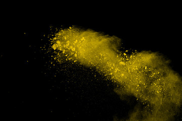 Abstract of yellow powder explosion on black background. Yellow powder splatted isolate. Colored...