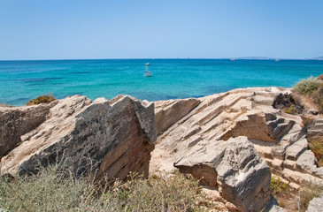 Fototapeta na wymiar Coastal rock landscape and small boats in turquoise sea with horizon on a sunny summer day in Mallorca, Spain.