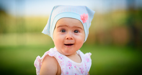 Baby girl infant looking at camera with funny expression on her face and big brown eyes