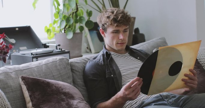 Young adult male looking at vinyl record