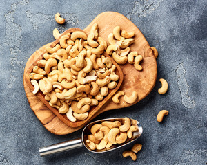 Roasted cashew nuts and scoop on gray background. Top view.