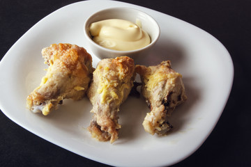 Baked poultry meat and mayonnaise on white plate. Delicious and dietary lunch or dinner on dark background