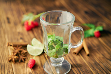 cold tea cocktail with ice and straw on wood board and blue background