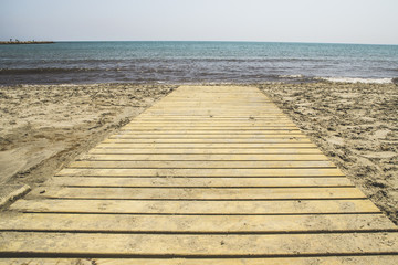 Fototapeta premium footbridge of wooden boards with direction to the sea