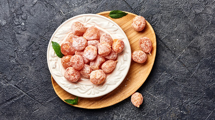 Dried sweet kumquat under powdered sugar on plate. Top view of dessert.