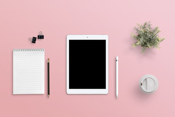 Female work table with a tablet. Blank screen for mockup. Pink surface. Flat lay, top view.