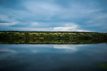 Foto op Canvas A simple landscape in the Rostov region in Russia, the river - Seversky Donets, Don. Spring is the beginning of summer. Green vegetation, trees. Cool fresh lake water. Colorful sky and its reflection  © Анна Иванова