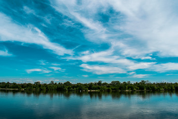 A simple landscape in the Rostov region in Russia, the river - Seversky Donets, Don. Spring is the beginning of summer. Green vegetation, trees. Cool fresh lake water. Colorful sky and its reflection 