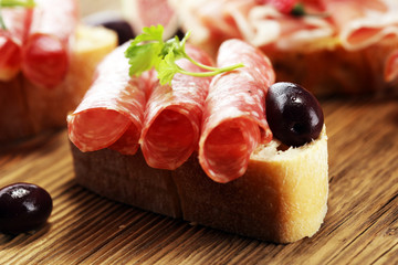 Sandwich with prosciutto or salami or crudo. Antipasti gourmet bruschetta snack.