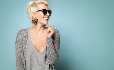 Attractive blonde in stylish clothes and sunglasses. Lovely female laughing and looking away. Copy...