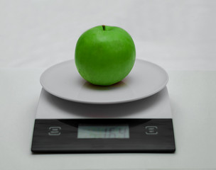 Grocery scales on a white background. The Apple green on the scales.