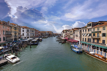 Fototapeta na wymiar Canal Grande di Venezia, con cielo nuvoloso, tra gondole e turisti