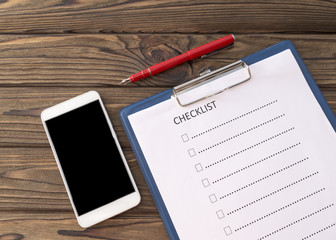 mobile phone, checklist, ballpoint pen on the wooden desk. concept of business planning.