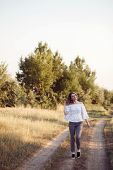 Young woman standing on a wheat field with sunrise on the background