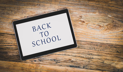 Back to school tablet on rustic wooden background.