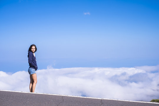 beautiful standing young female caucasian people at the side of the road with amazing and blue cloudy background. travel and enjoy the nature concept for people