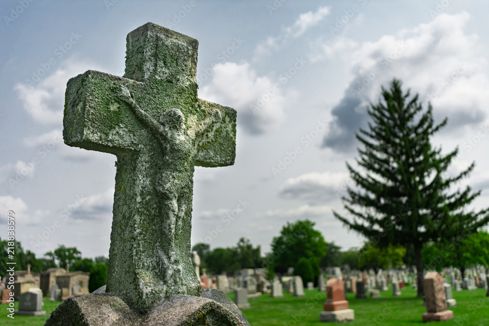 Wall mural old cross on top of a tombstone at a cemetery