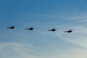 Fototapeta na wymiar Flight of four military helicopters. Air parade. Air force day. Side view. Flight formation. Serene blue sky and white clouds.