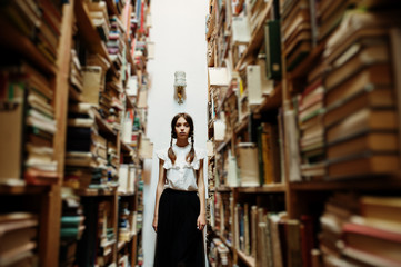 Girl with pigtails in white blouse at old library.
