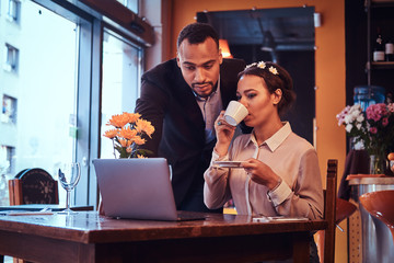 Attractive African-American couple at a business meeting in the restaurant discussing working moments with laptop at lunchtime.