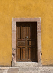 Colonial style wooden door with yellow wall in Guanajuato Mexico.