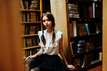 Girl with pigtails in white blouse at old library.