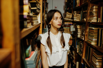 Girl with pigtails in white blouse at old library.