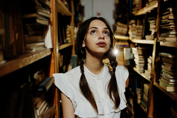 Girl with pigtails in white blouse at old library.