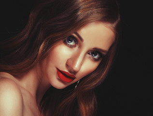 Fototapeta premium Blonde fashion girl with long and shiny curly hair. Red lips and bright make up. Over black background.