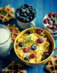 Healthy breakfast. Corn flakes with raspberries and blueberries, granola with yogurt and berries, wafers and milk. A great start to the day. Top view.