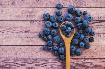 Fresh and juicy blueberries in a wooden spoon on wooden table with copyspace. Healthy food concept.