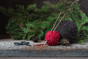 Colorful tweed wool yarn with wooden needles with a firtree background, winter knitting postcard, copyspace