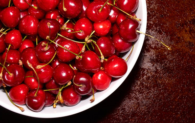 Pile of fresh cherries in the white bowl on the table top angle background