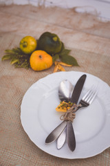 Seasonal table setting with small pumpkins and yellow and green leaves