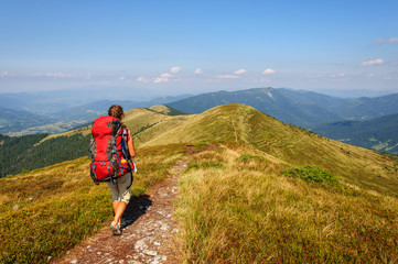 Fototapeta na wymiar girl with a big backpack rises to the mountains. Ukraine