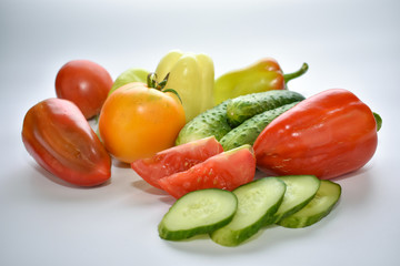 green cucumbers, red bell peppers and tomatoes on a white background, vegetable assortment
