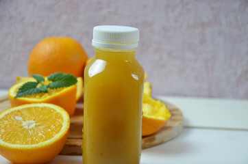 Bottle of orange juice studio shot orange organic freshly squeezed juice in a small plastic bottle on a colorful background next to sliced orange and a mint leaves