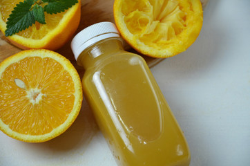 Bottle of orange juice studio shot orange organic freshly squeezed juice in a small plastic bottle on a colorful background next to sliced orange and a mint leaves