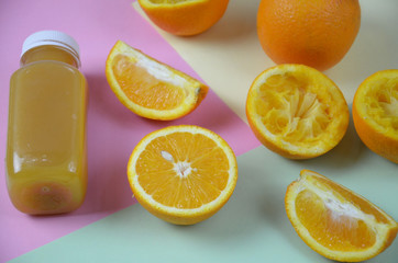 Bottle of orange juice studio shot orange organic freshly squeezed juice in a small plastic bottle on a colorful background next to sliced orange and a mint leaves