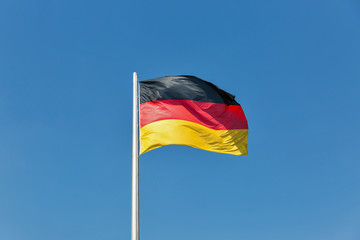 German flag on the flagstaff waving against clear blue sky