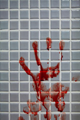 Smeared fresh bloody handprint or bloodstains with streaks on bathroom tiles wall. Horror halloween or Violent Crime or Homicide murder or Domestic violence concept. © wanessa_p