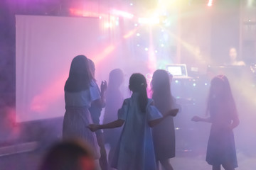 Naklejka premium blur Light in club party Show And Silhouette hands of audience crowd people use smart phones enjoying the club party with concert. Blurry night club DJ party people enjoy of music dancing sound.