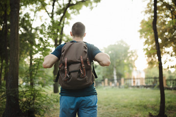 Backpack on a man, rear view of male tourist hiking travelling in park