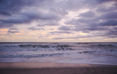 Fototapeta na wymiar Horizon to shore waves at a cloudy, colourful sunset in Central America