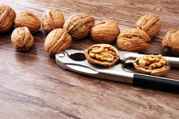 Walnut kernels and whole walnuts on brown wooden table.