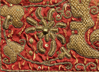 Fototapeta premium Vintage hand embroidery - golden floral pattern on red background