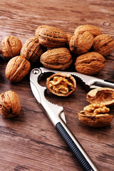 Walnut kernels and whole walnuts on brown wooden table.