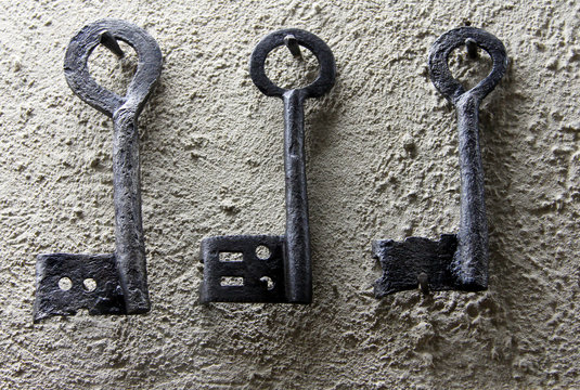 Three vintage black keys on white wall