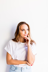 Fototapeta premium Portrait of the young thinking woman looking up sideways on white background.