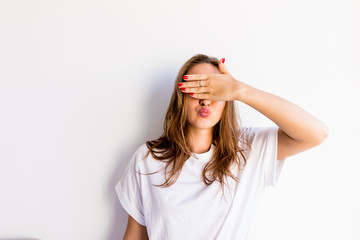 Fototapeta premium Young smile woman covering her eyes isolated on a white background